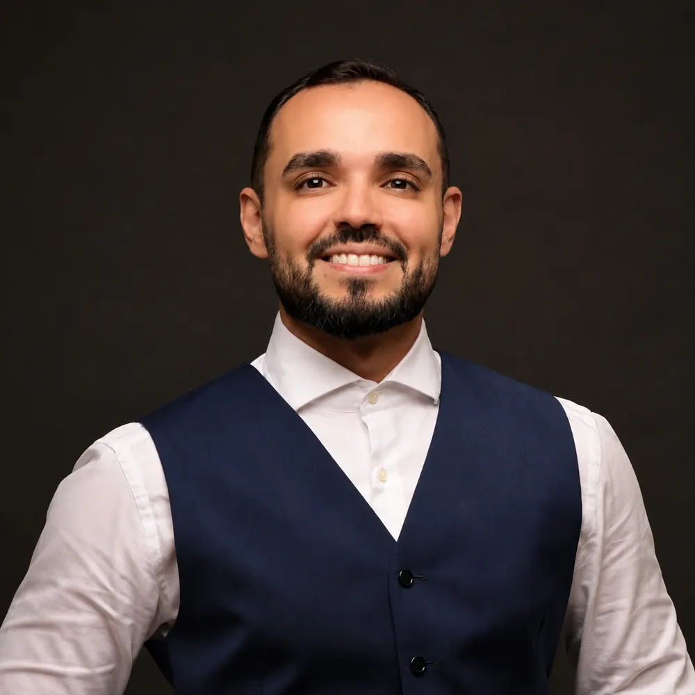 Retrato do Dr. Iago Bezerra, médico, de colete azul-marinho e camisa branca